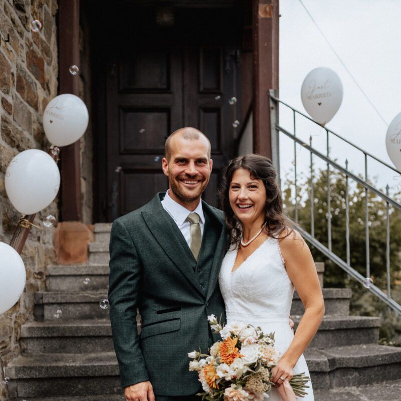 Bild: Brautpaar Leah und Benedikt Hartmann auf den Stufen der Mundartkirche in Friedensdorf