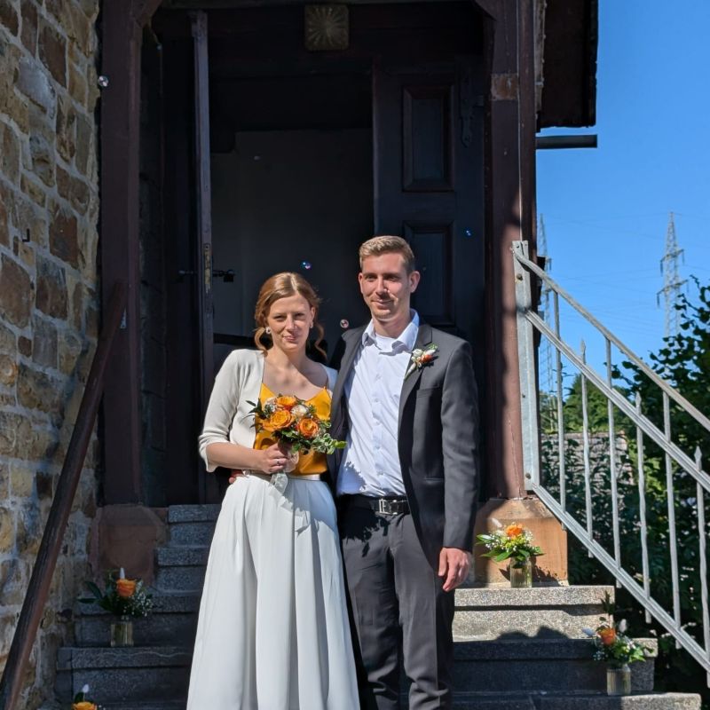 Foto: Das Brautpaar Nils und Leandra Demper auf den Stufen der Mundartkirche in Friedensdorf